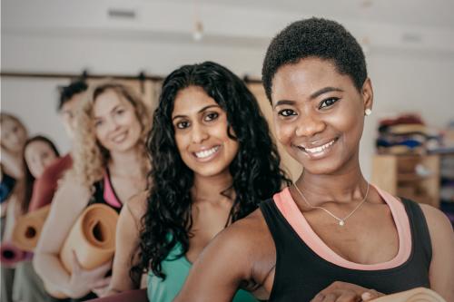 People smiling while holding yoga mats